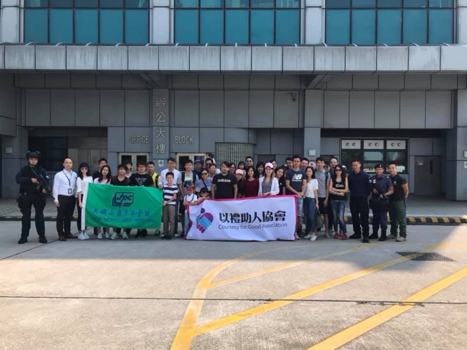 Participants hold an Association banner for a group photo outside a building.
