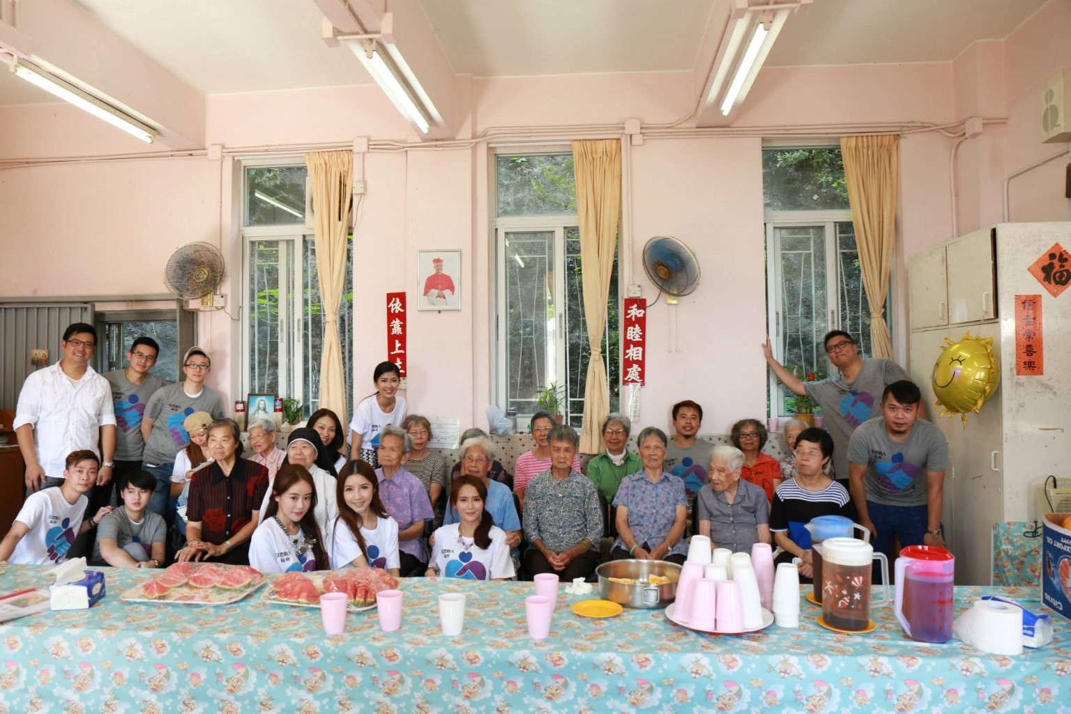 Volunteers and older people gather around an activity table at a community event.