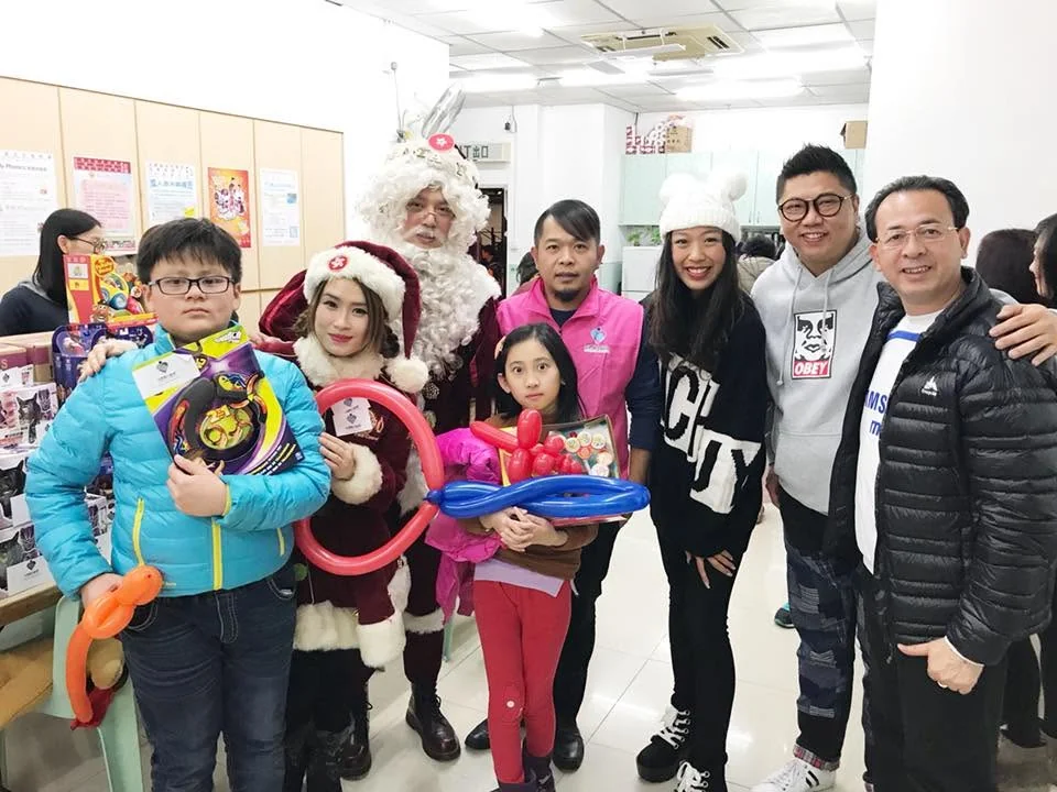 Children holding toys and balloons, posing indoors with Santa Claus and adults.
