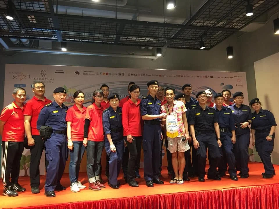 Volunteers and uniformed service personnel posing on an event stage.